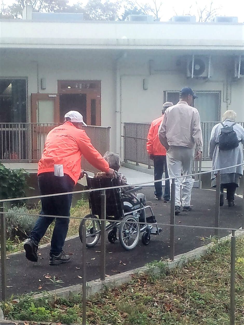 車椅子を押しながらスタッフジャンパーを着用されている写真