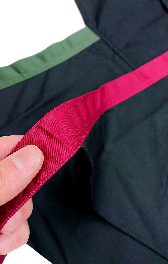 真っ黒の胸当てエプロンの腰紐を赤と緑の付け替えています。<br>こんな感じで縫製のキレイさもご覧くださいませ。<br>弊社の熟練技術を持っている縫製スタッフがミシンで仕上げています。